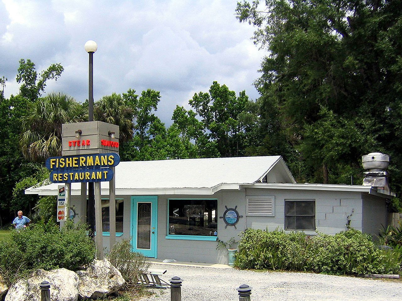 a fisherman 's restaurant is surrounded by trees and gravel