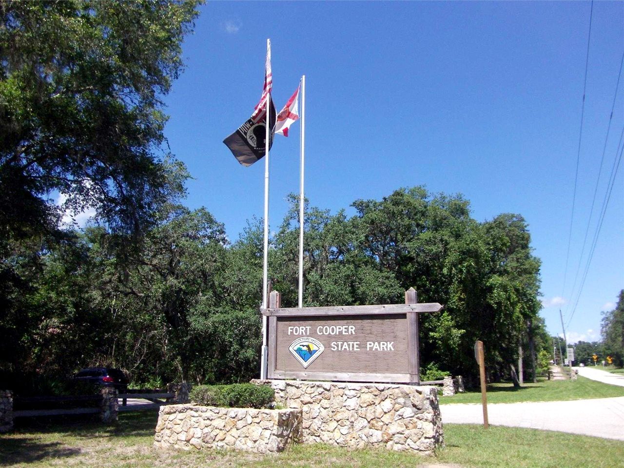 a sign for a park with two flags flying in front of it