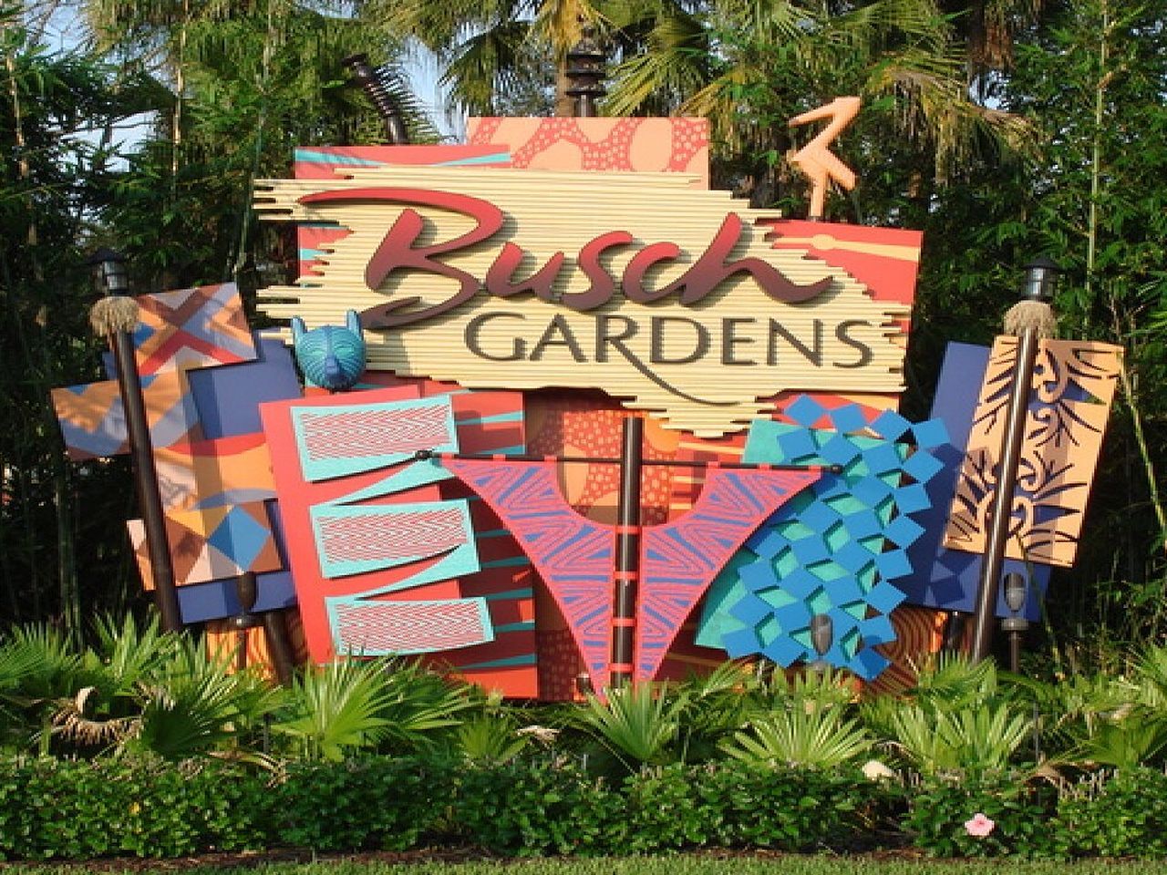 a colorful sign for busch gardens is surrounded by trees