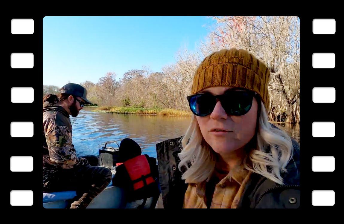 a woman wearing sunglasses and a hat is sitting in a boat on a river .