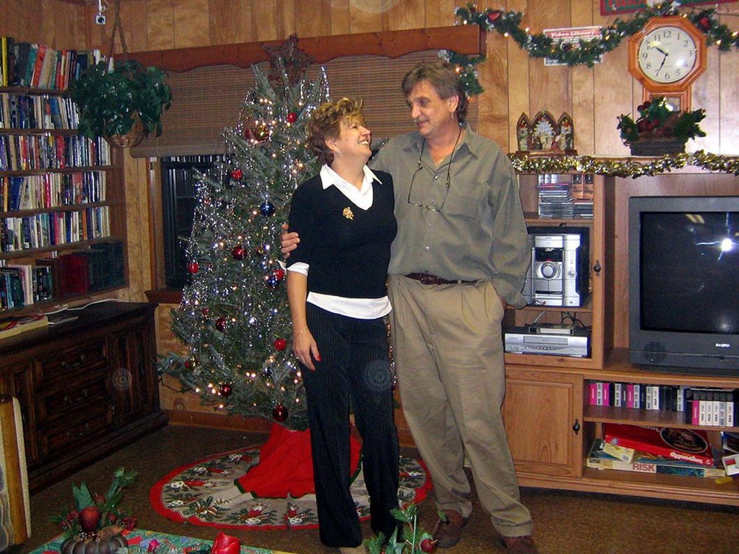 a man and woman standing in front of a christmas tree