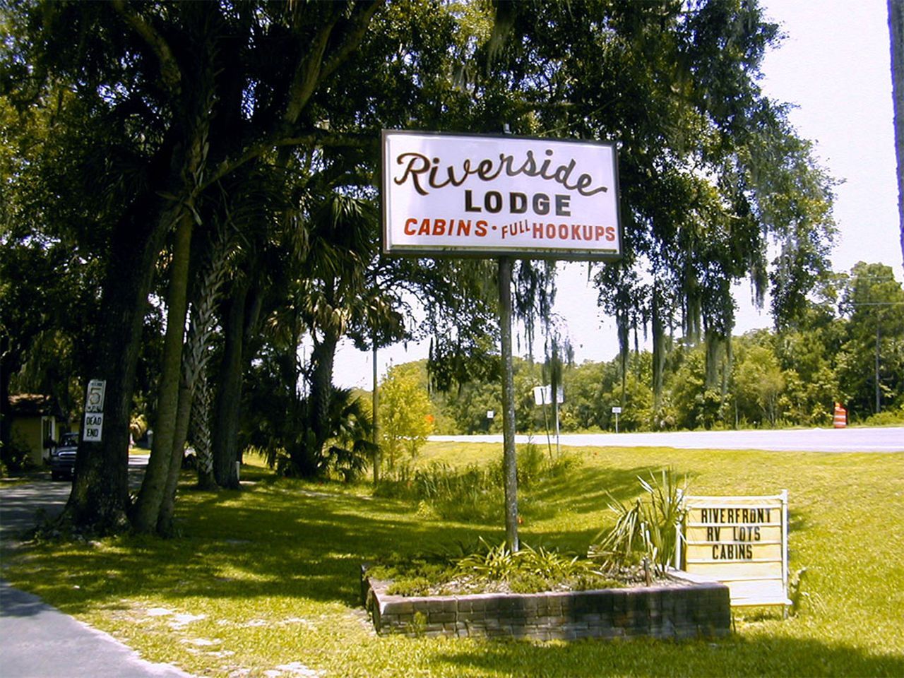 a riverside lodge sign is in the middle of a grassy field