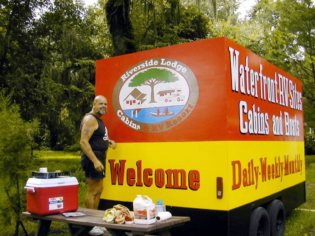 a man stands in front of a trailer that says welcome