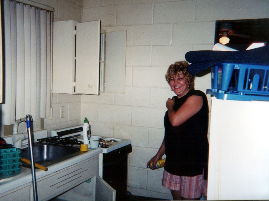 a woman is standing in a kitchen next to a refrigerator