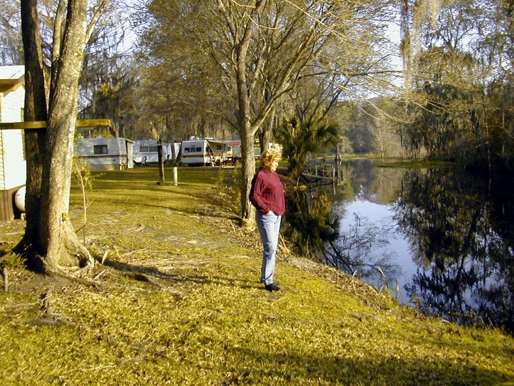 a woman in a red sweater is standing next to a river