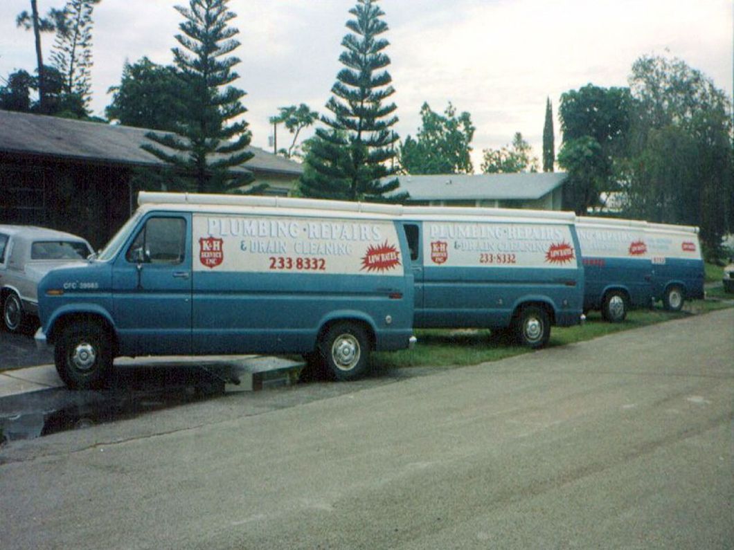 a row of blue vans are parked on the side of the road