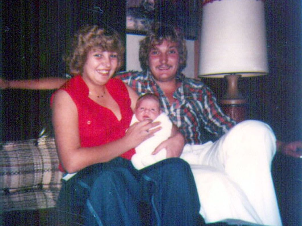 a man and a woman are sitting on a couch holding a baby .