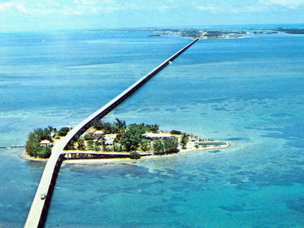 an aerial view of a bridge over a small island in the middle of the ocean