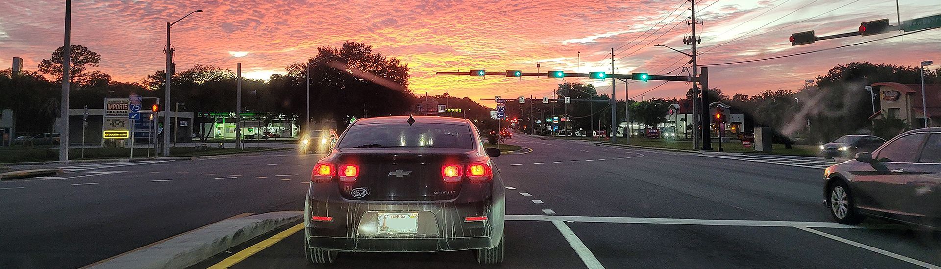 a car is driving down a street at sunset .