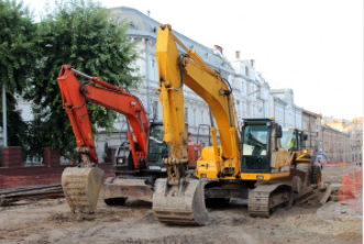 Two modern excavators in Cheyenne, WY in front of commercial building.