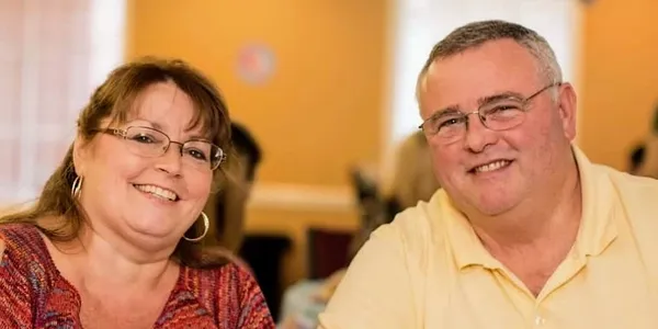 A man and a woman are smiling for the camera while sitting at a table.