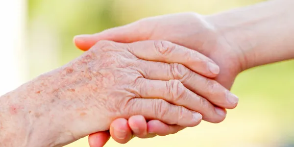 A young woman is holding an older woman 's hand.