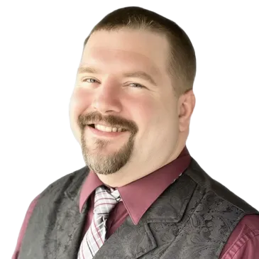 A man with a beard is wearing a vest and tie and smiling.