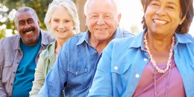 A group of elderly people are sitting next to each other and smiling.