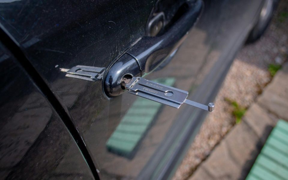 A close up of a car door being unlocked with a lock pick.