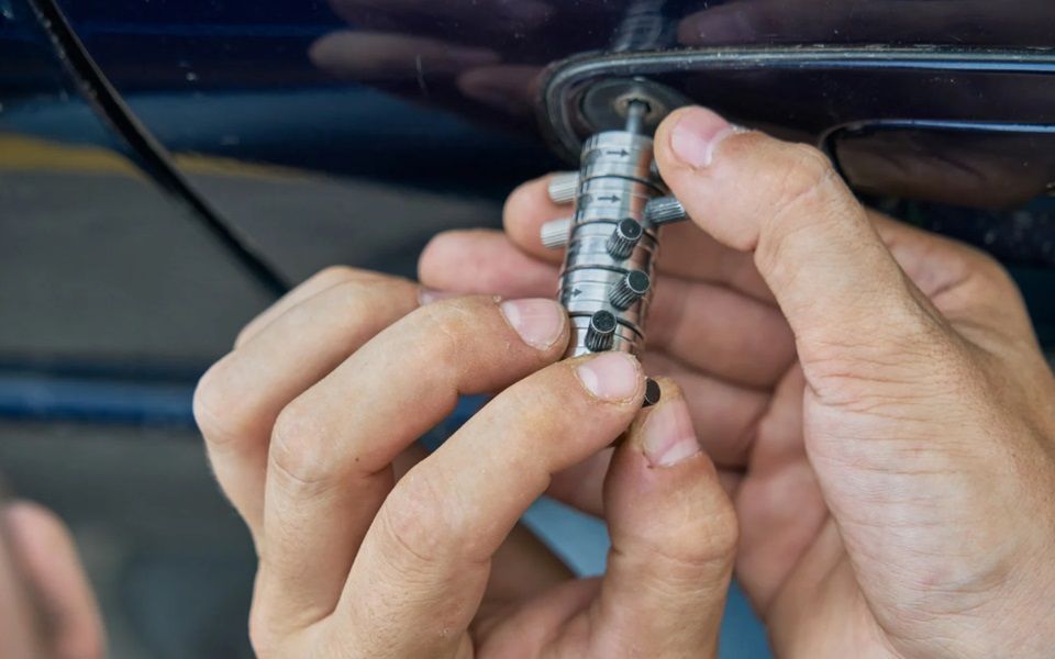 Hands holding a car door unlocking tool.