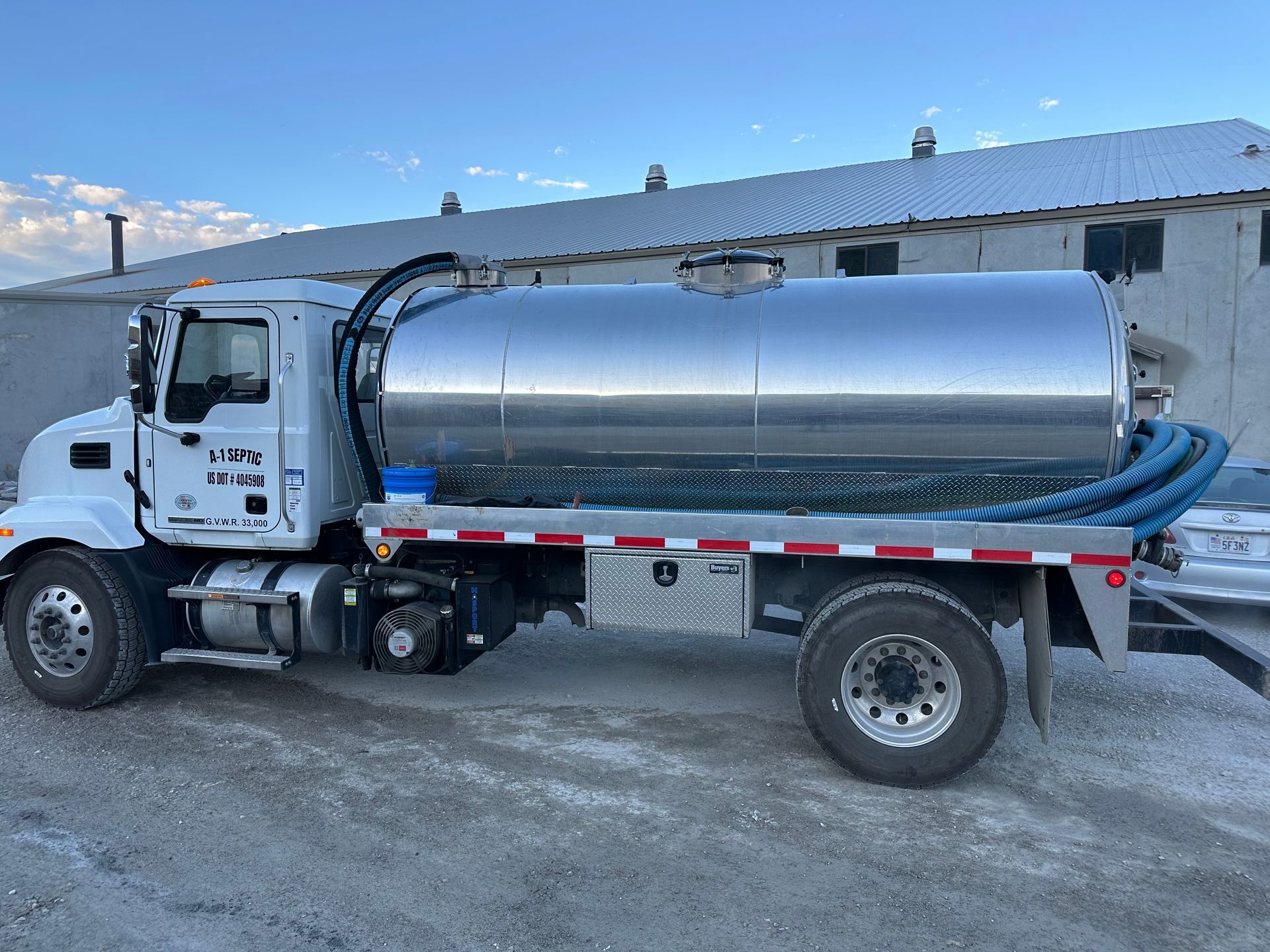A vacuum truck is parked in front of a building.