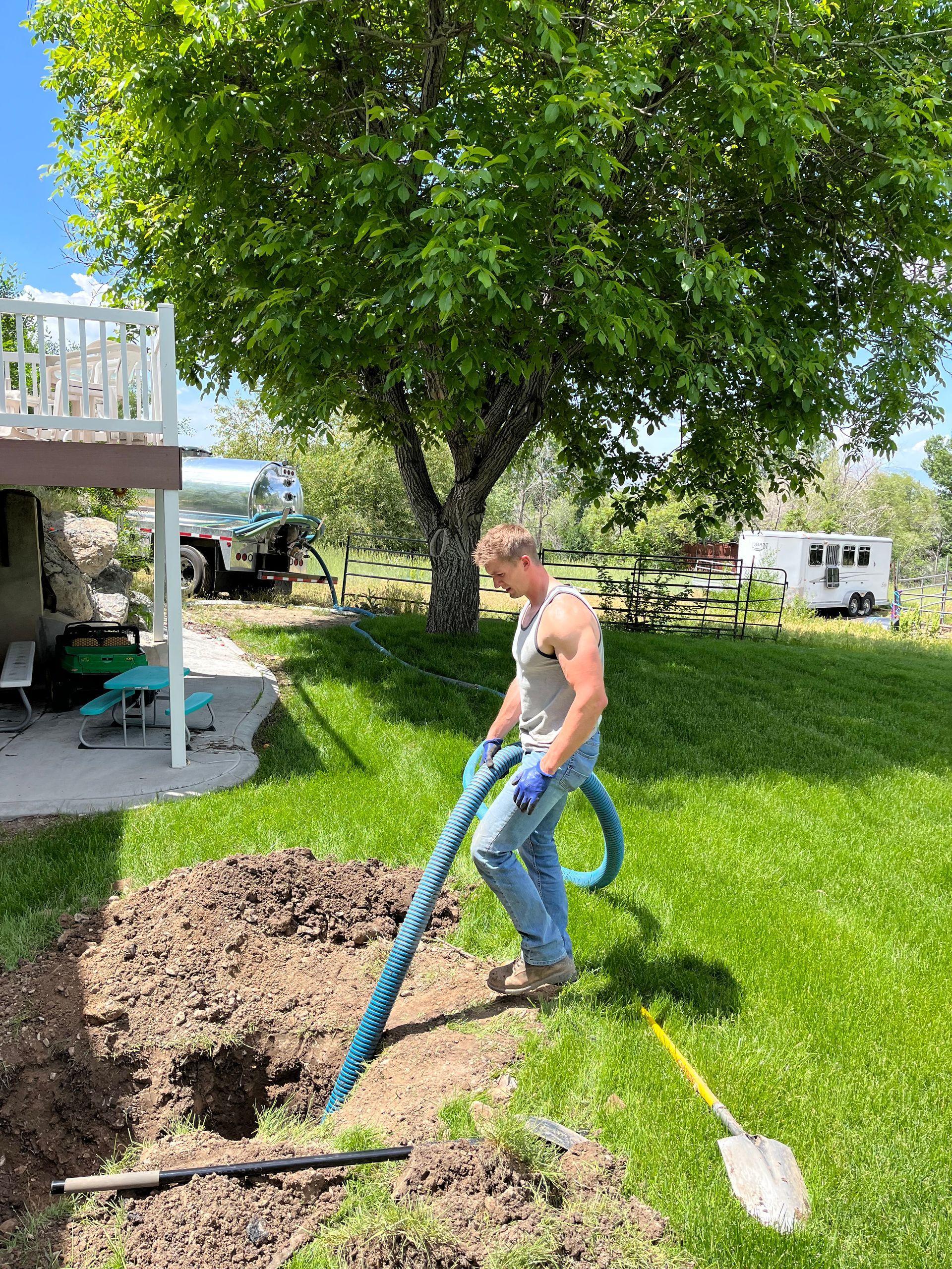 A man is using a vacuum hose to dig a hole in the ground.