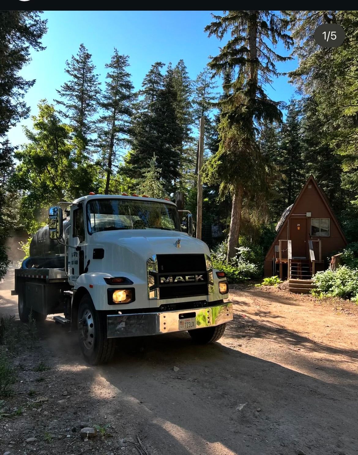 A mack truck is driving down a dirt road