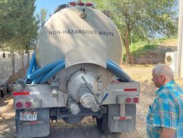 A man is standing in front of a vacuum truck.