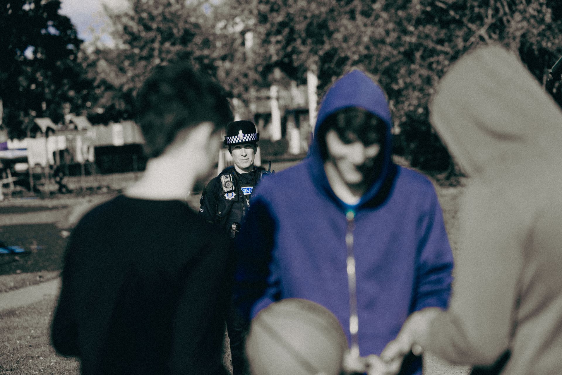 A group of people are standing in a park talking to each other.