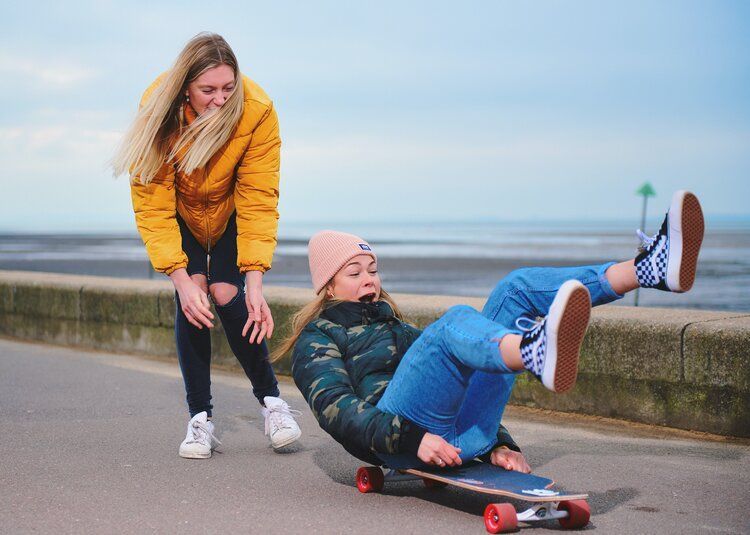 a woman is standing next to a girl on a skateboard .