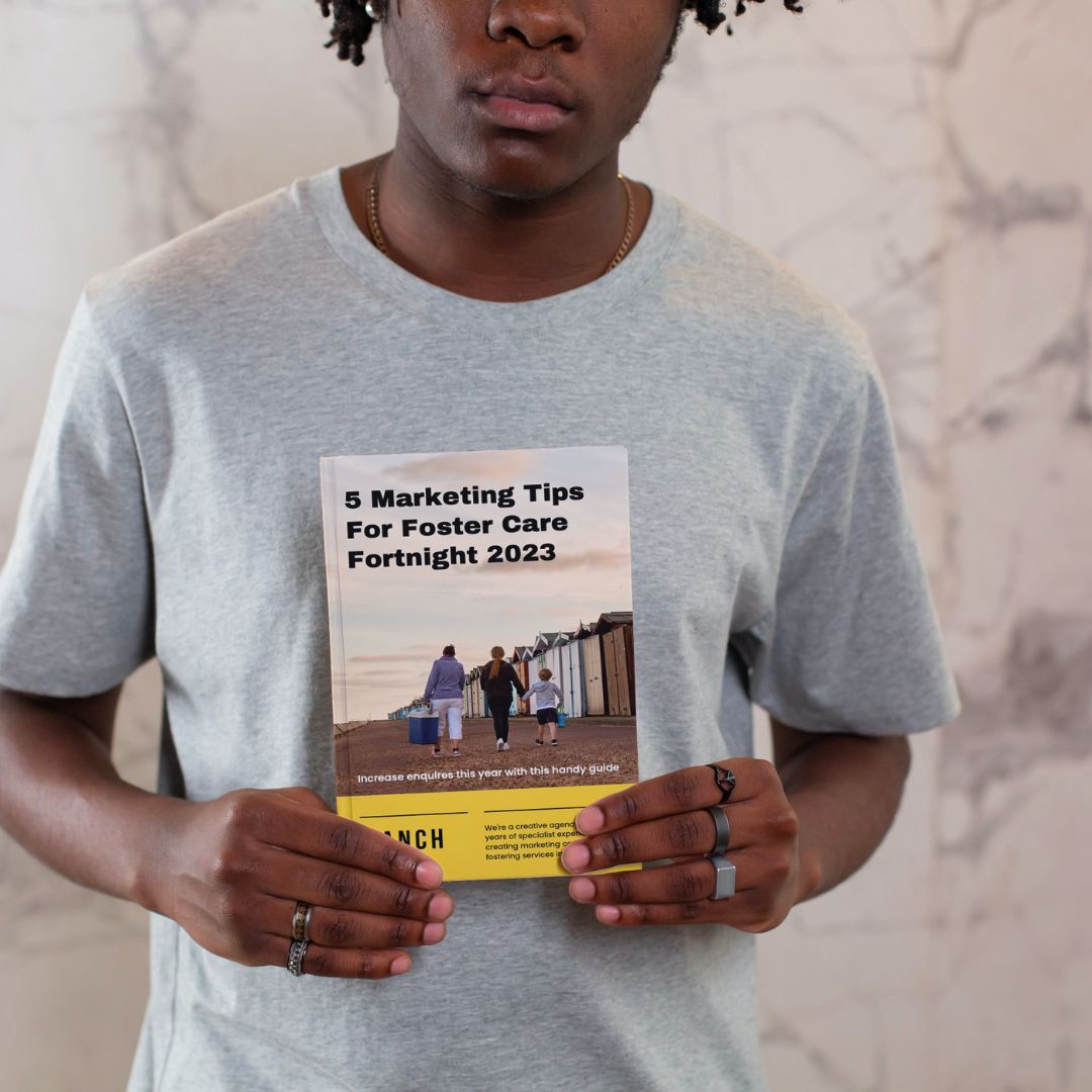 A man is holding a book titled marketing tips for foster care fortnight 2023