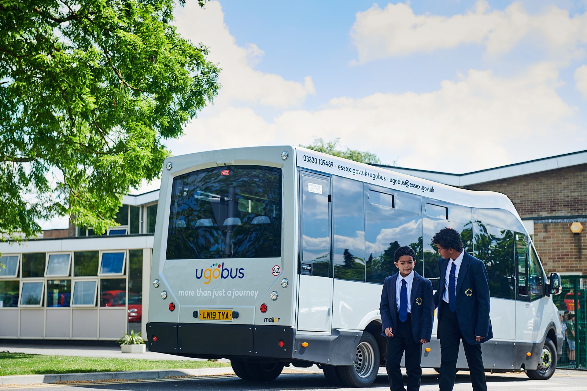 Two boys are standing in front of a school bus.