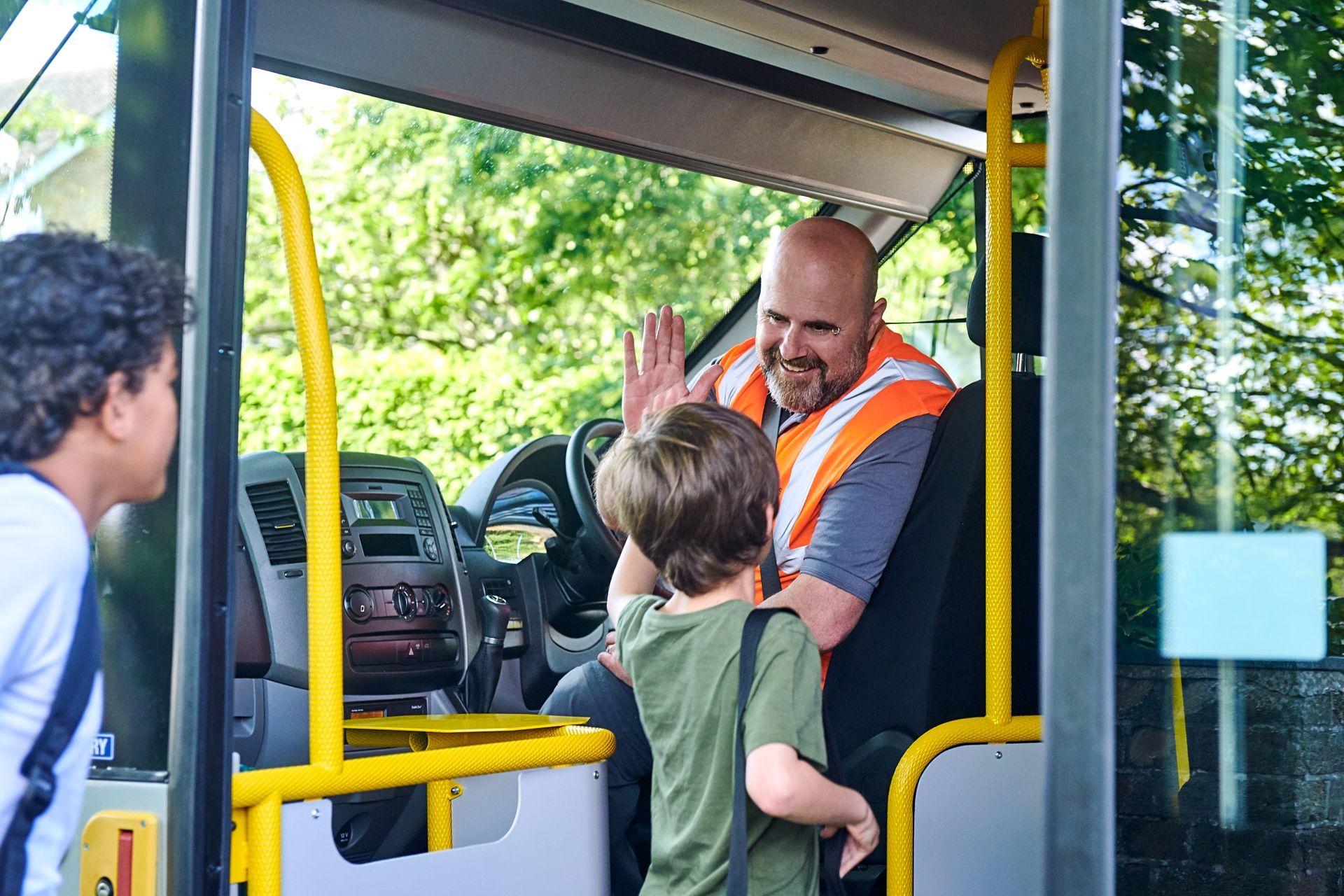 A man is giving a high five to a boy on a bus.