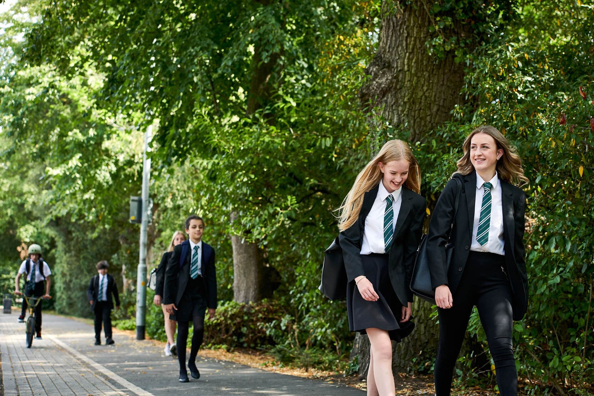 A group of school children are walking down a sidewalk.