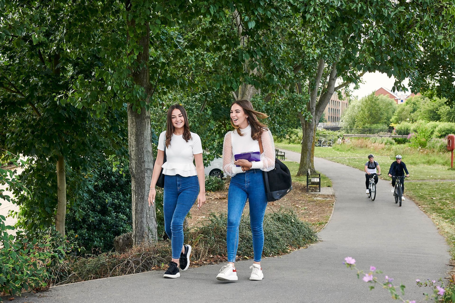 Two women are walking down a path in a park.