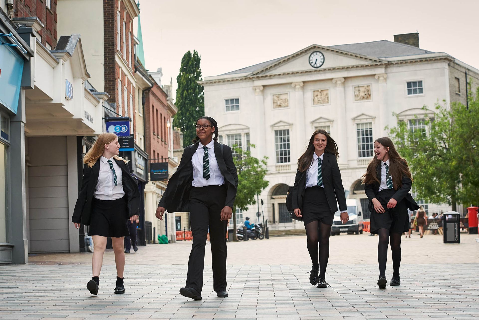 A group of young girls in school uniforms are walking down a city street.