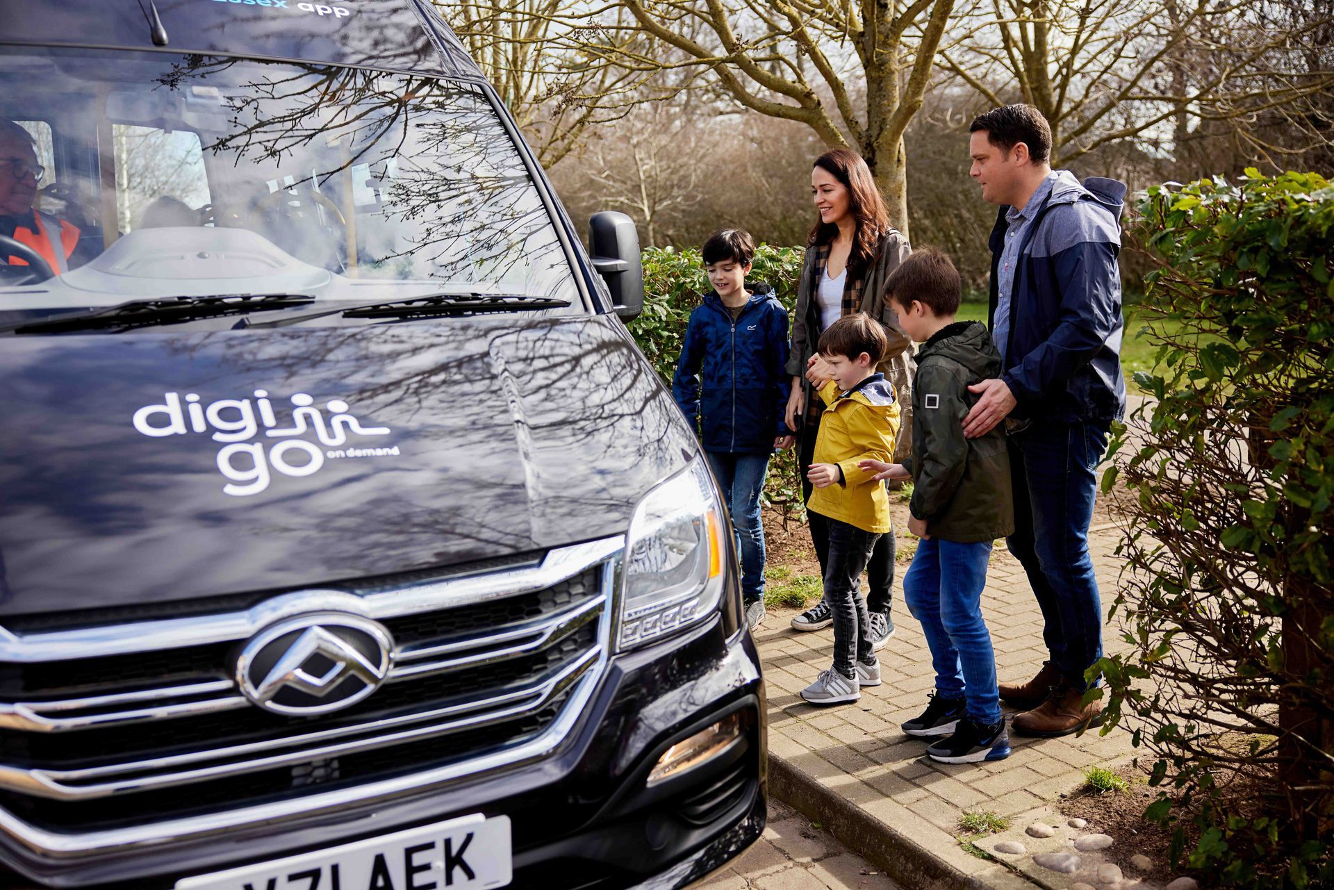 A family is standing in front of a black van.