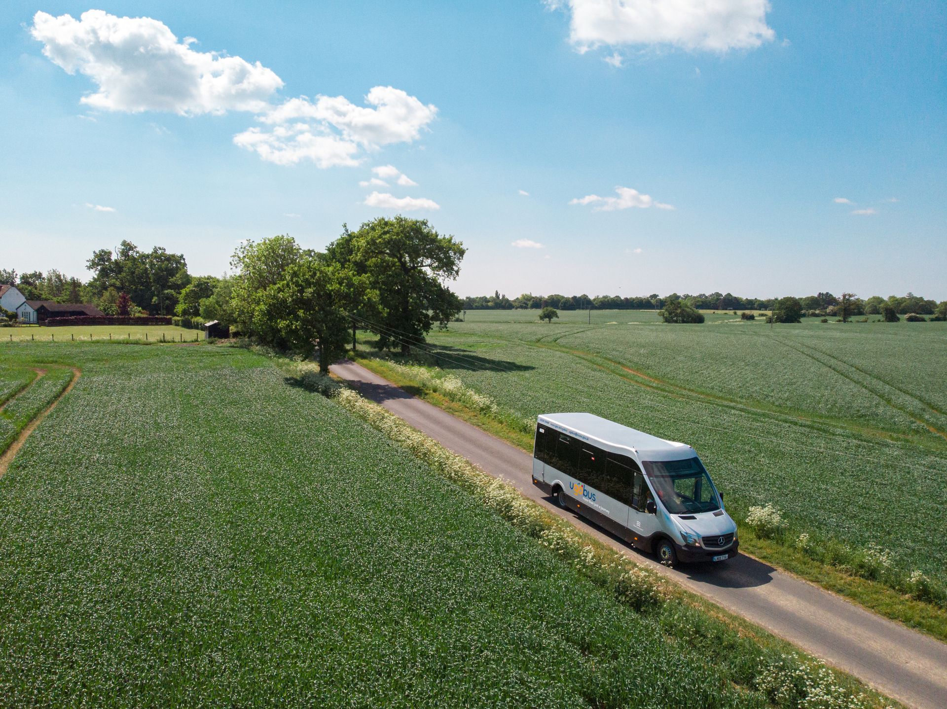 An aerial view of a white van driving down a country road.