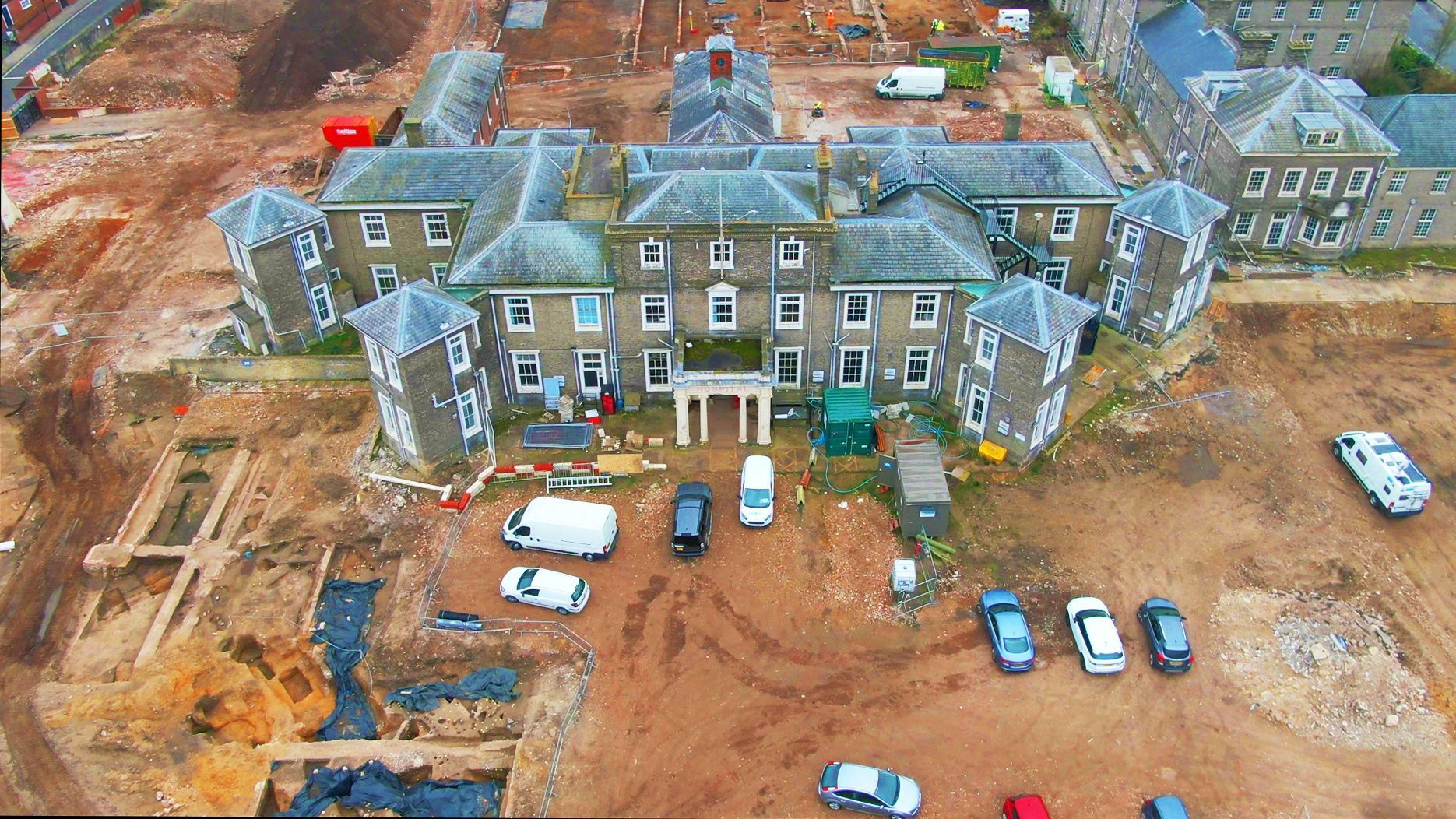 An aerial view of a building under construction with cars parked in front of it