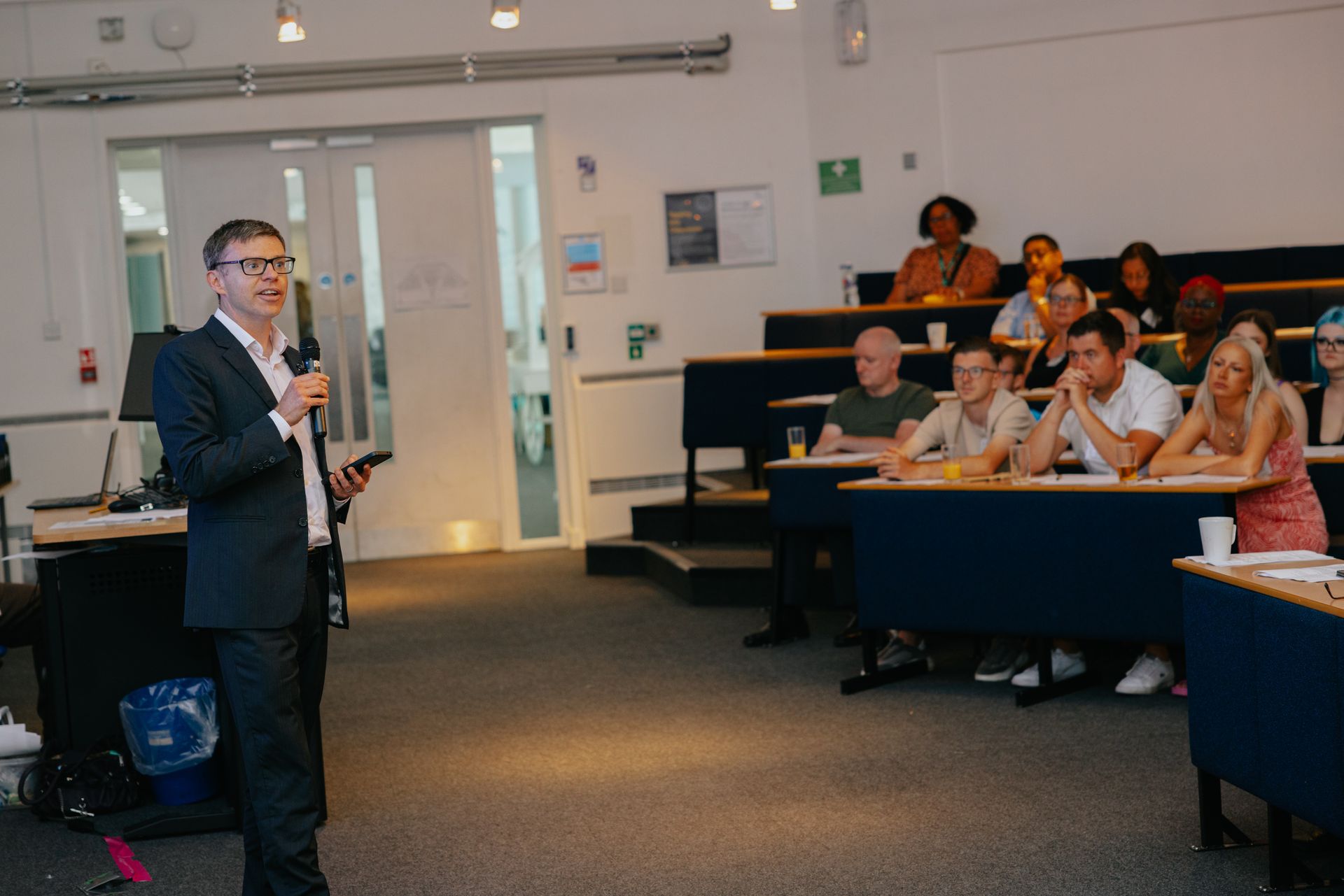 A man is giving a presentation to a group of people in a lecture hall.