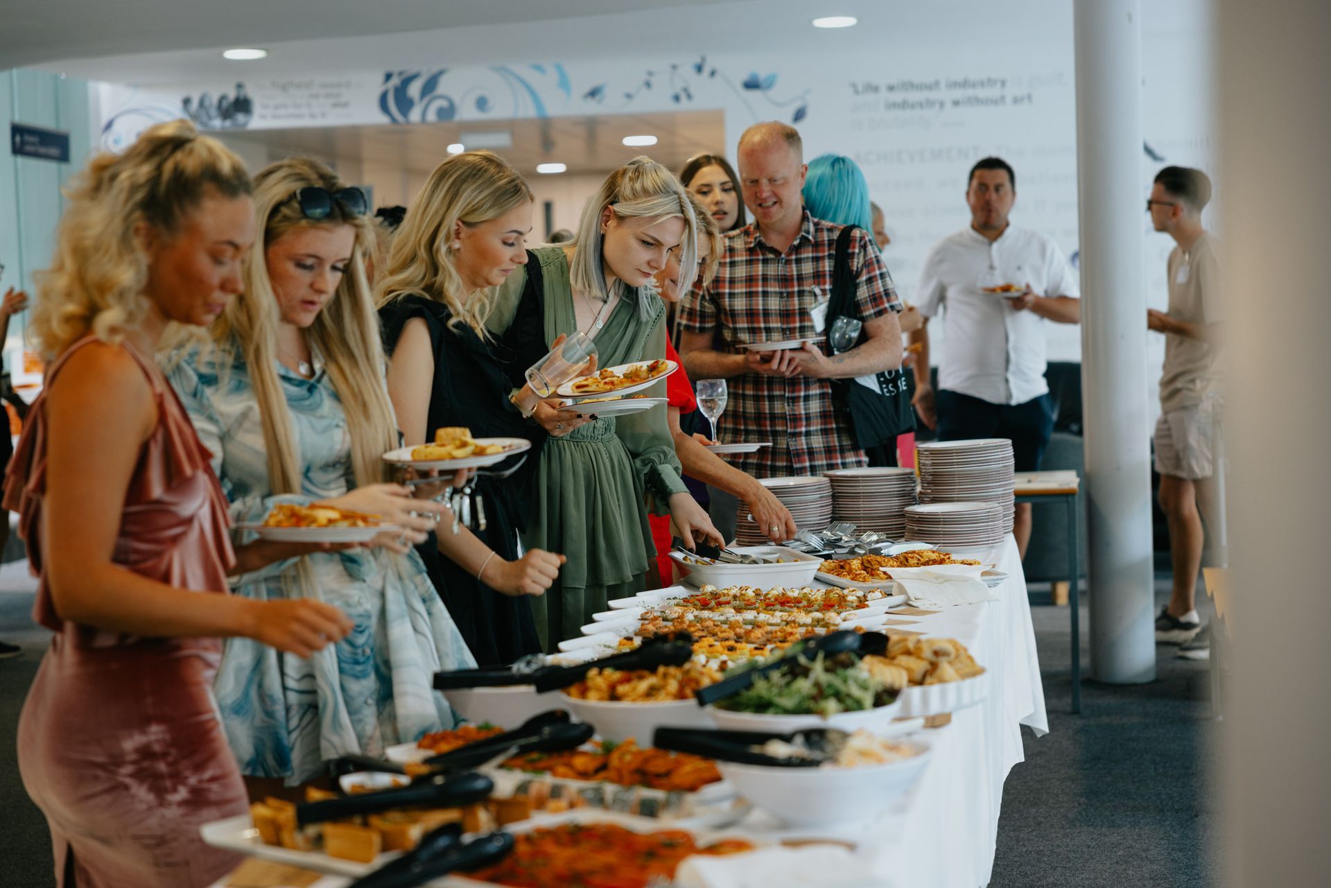 A group of people are standing around a buffet table eating food.