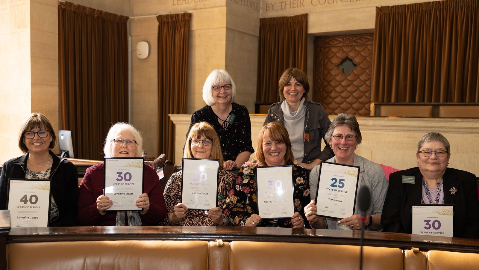 A group of women are sitting at a table holding signs.