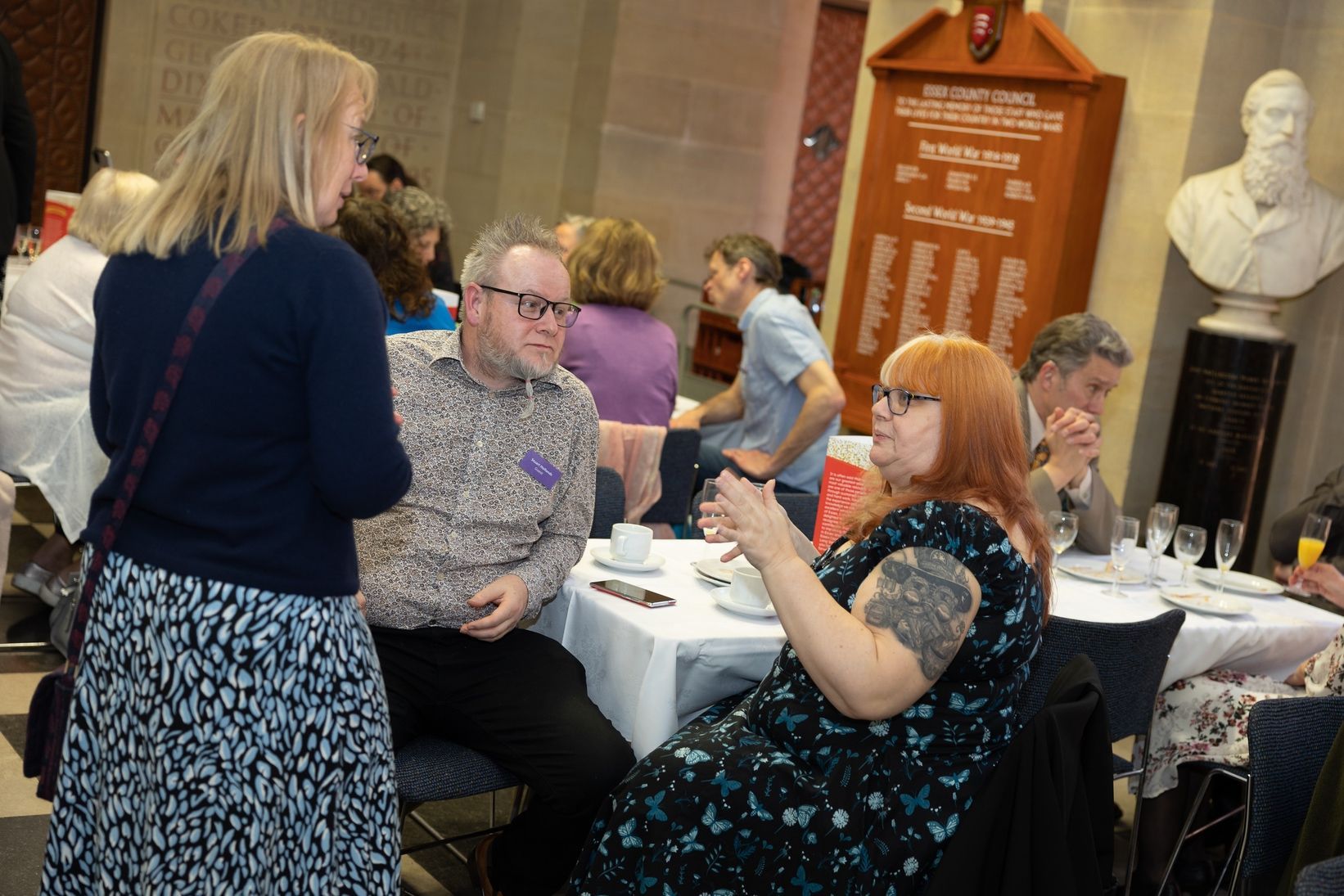A group of people are sitting at tables talking to each other.
