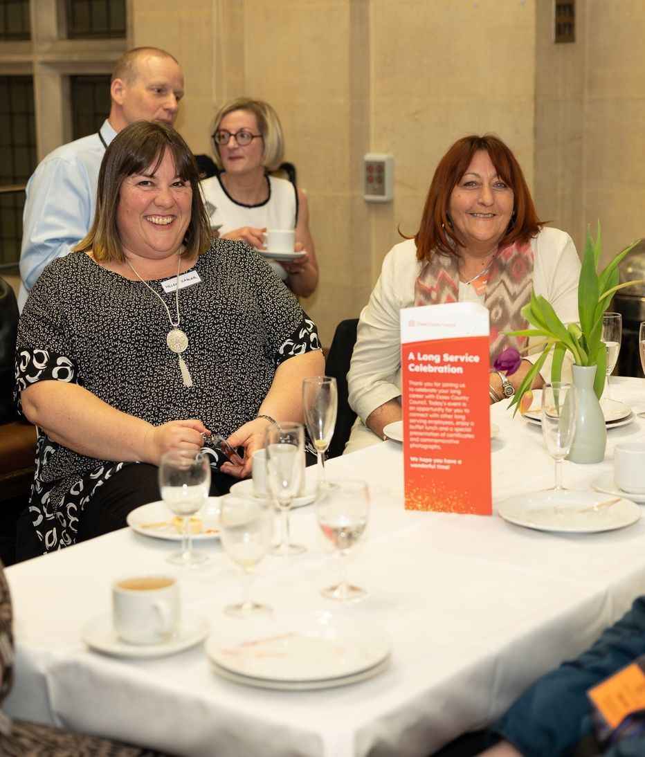 A group of people are sitting at a table with plates and glasses of wine.