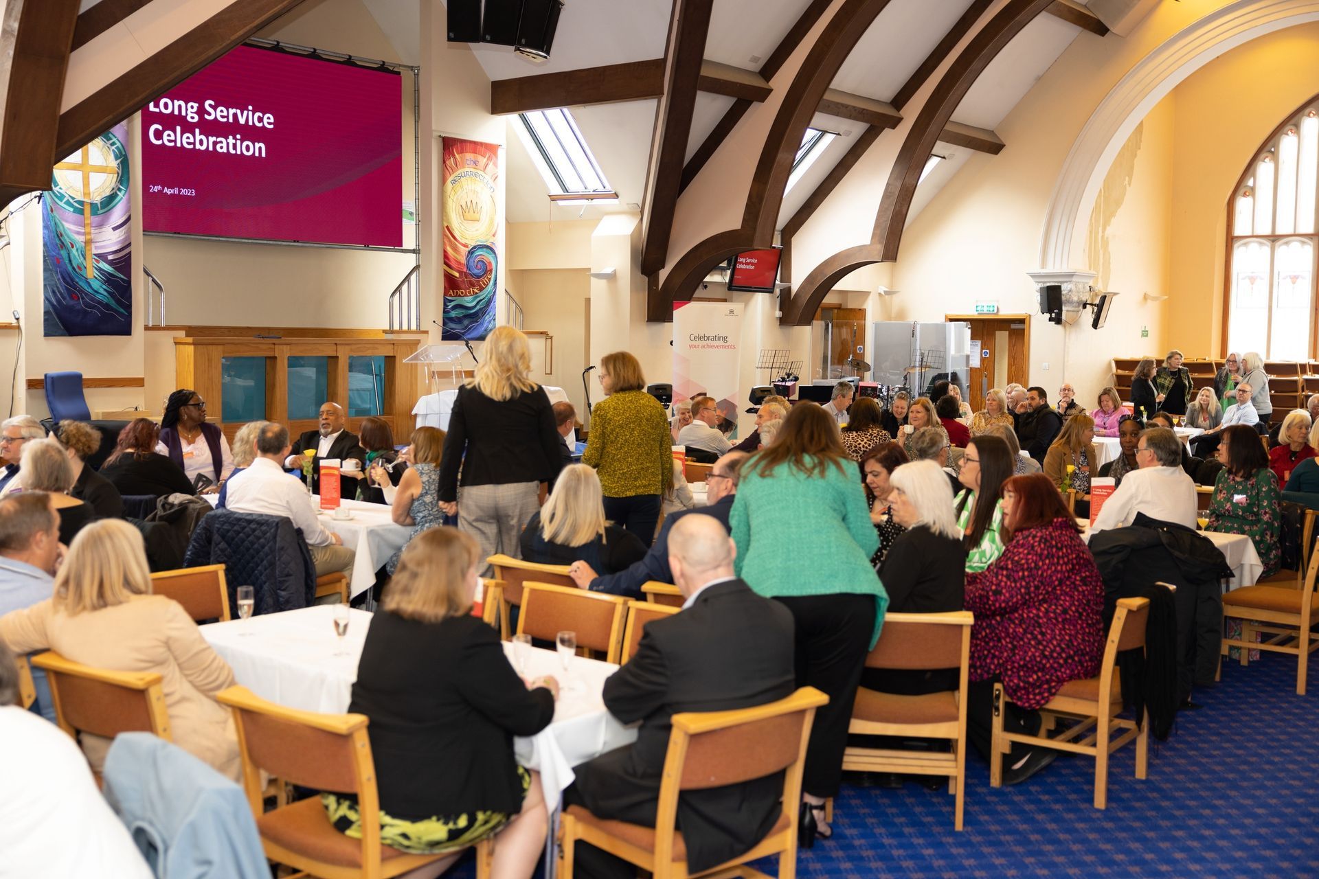 A large group of people are sitting at tables in a church.