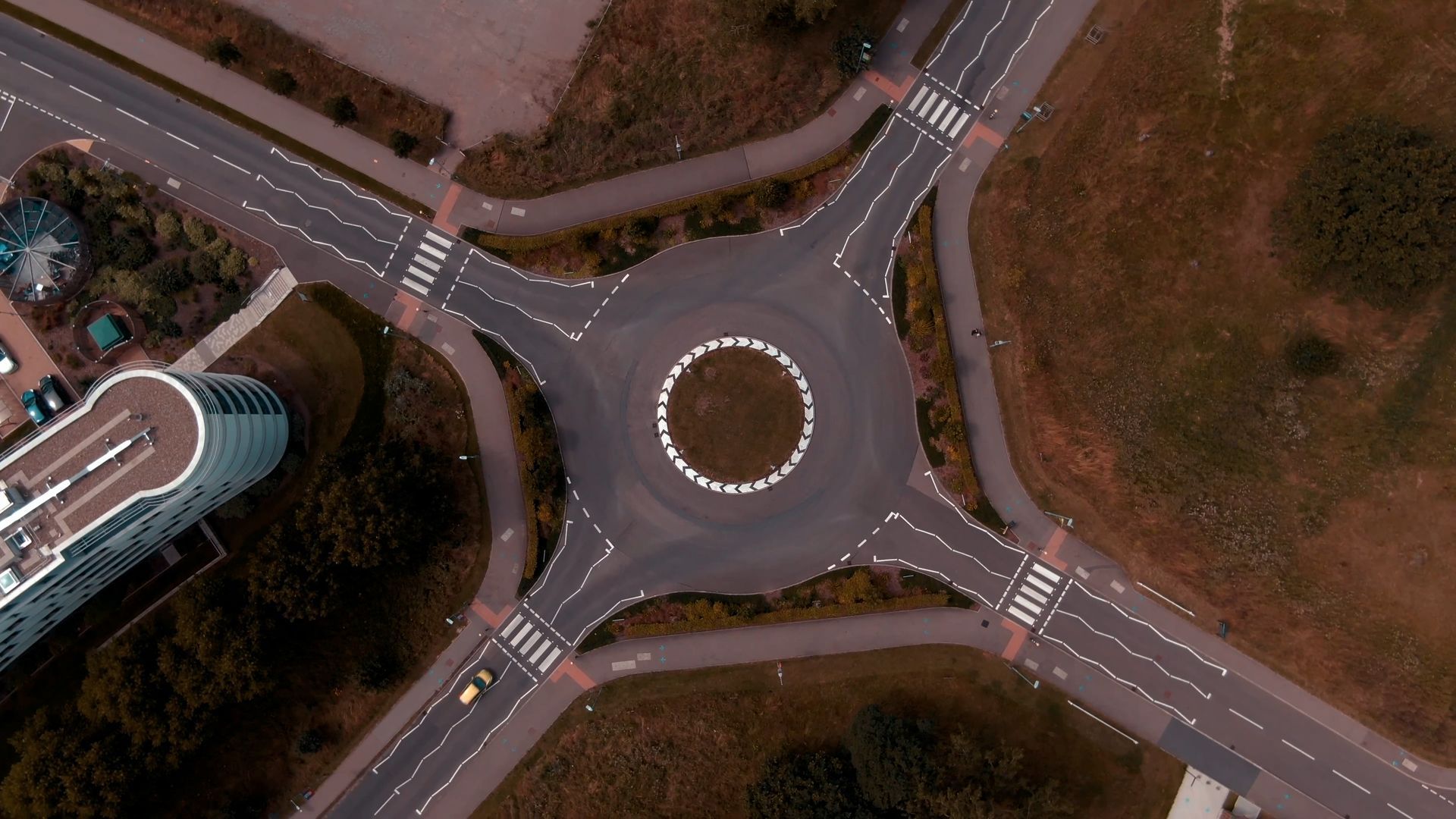 An aerial view of a roundabout with a building in the background.