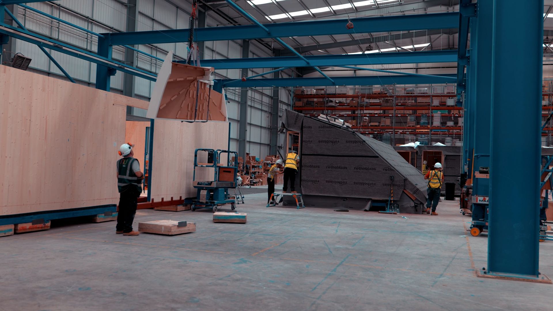 A group of construction workers are working in a large warehouse.