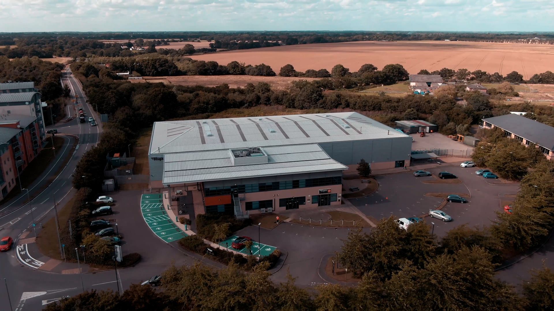 An aerial view of a large building surrounded by trees and a parking lot.
