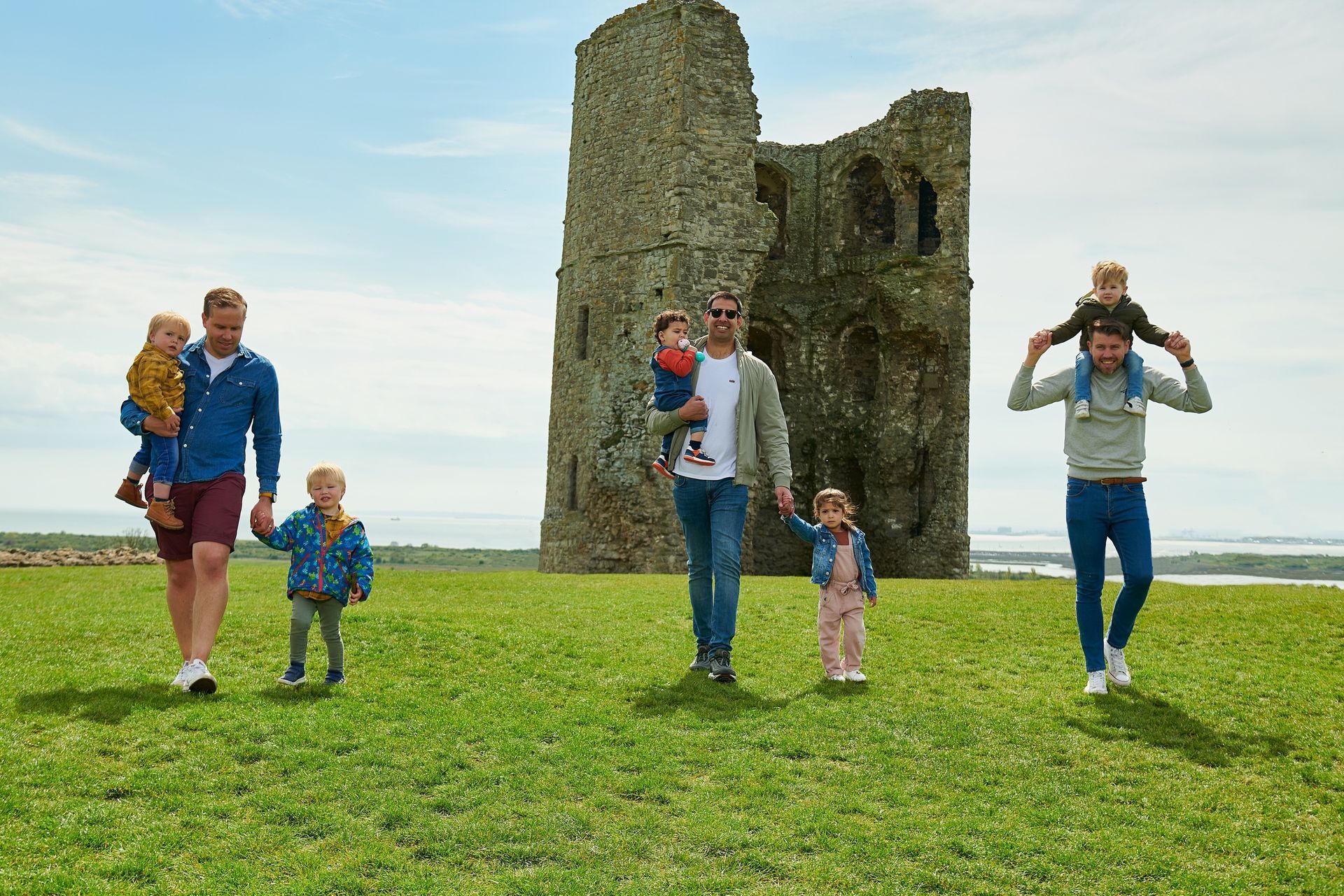 A group of people are walking in a field in front of a castle.