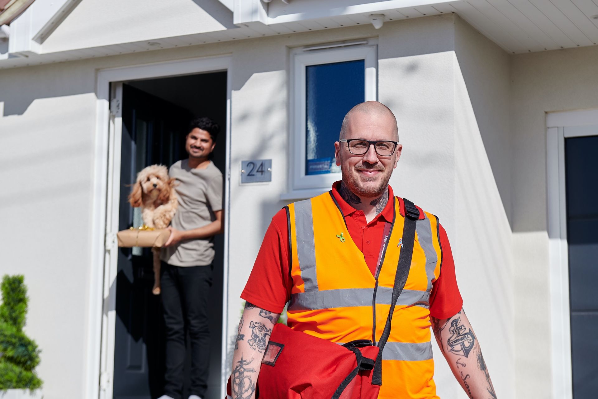 A man in an orange vest is standing in front of a door holding a dog.