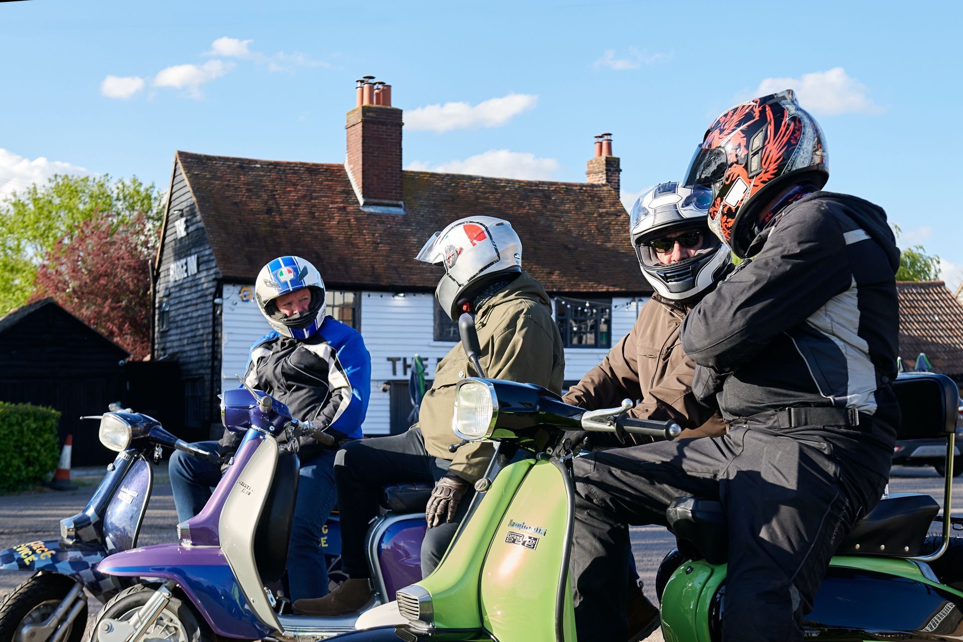 A group of people are riding scooters in front of a house.
