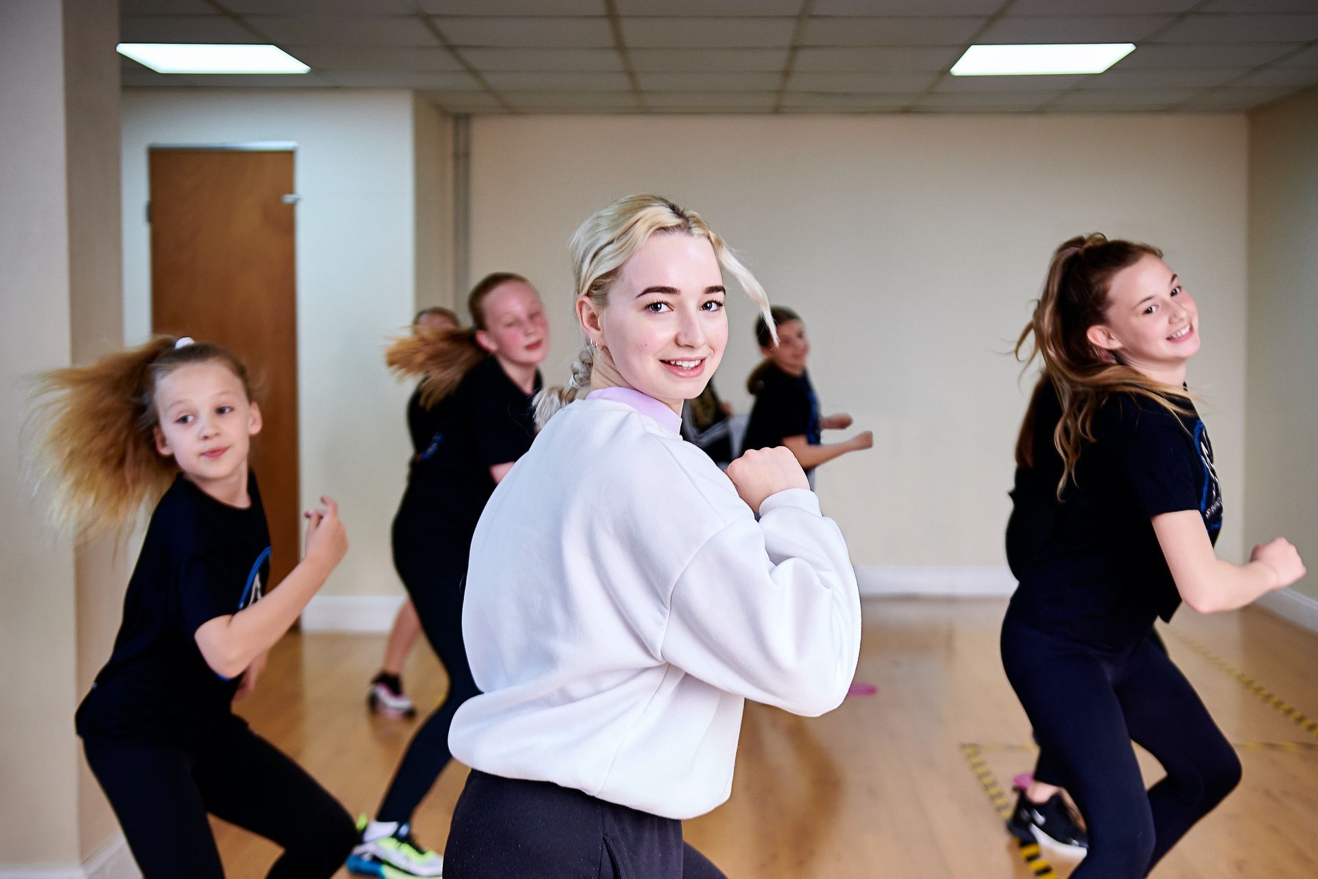 A group of young girls are dancing in a dance studio.