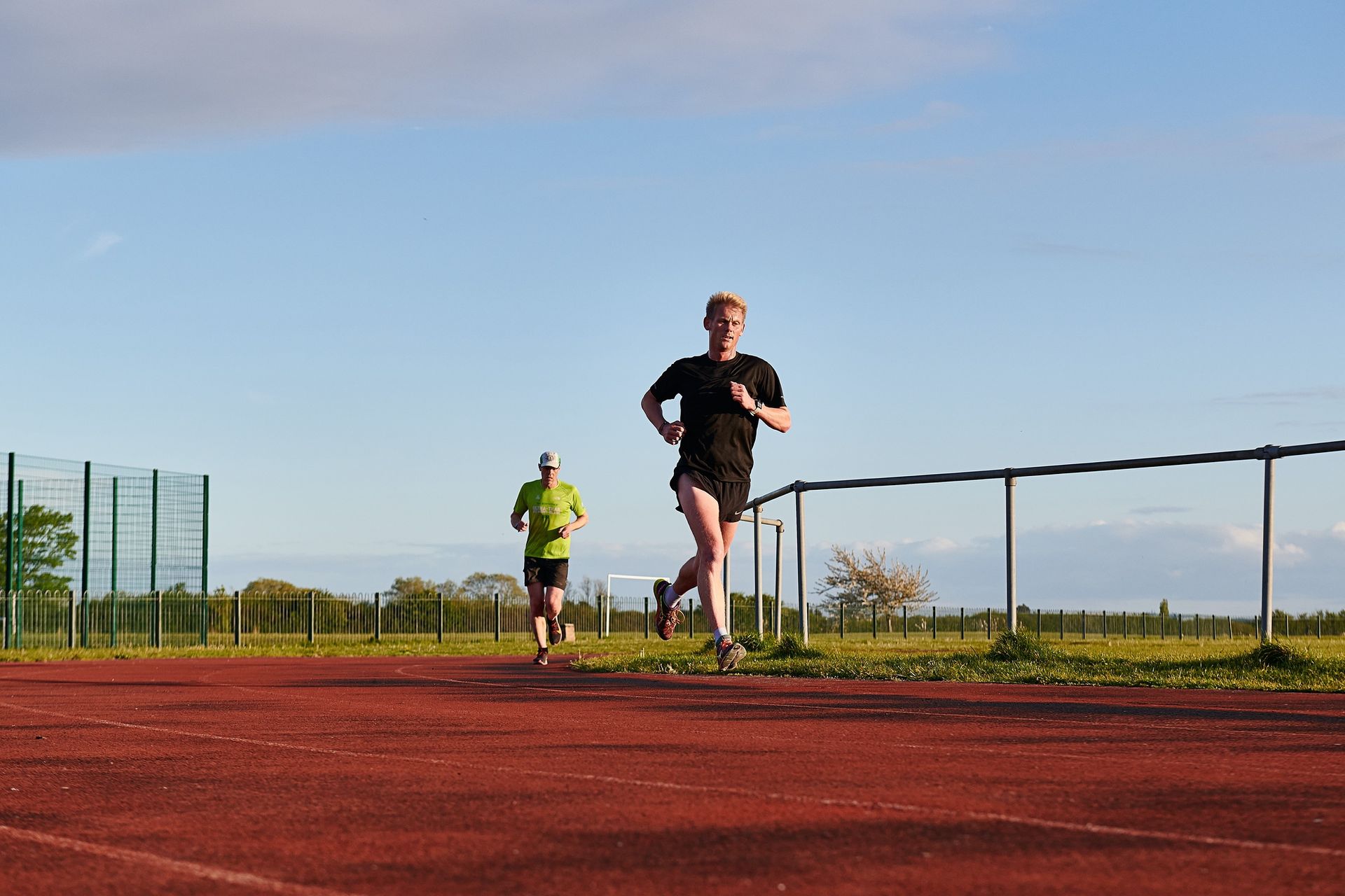 Two people are running on a track in a park.