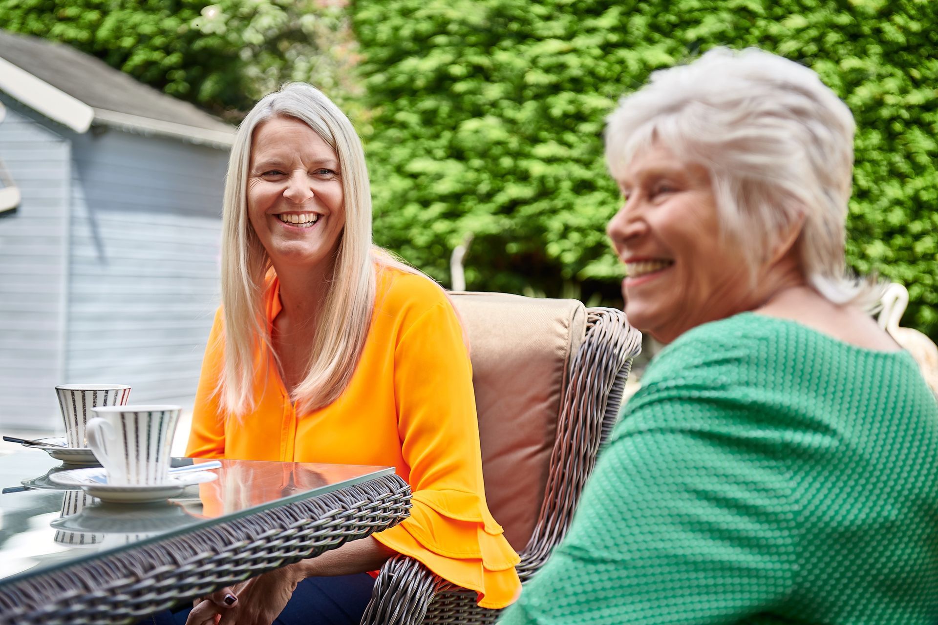 Two women are sitting at a table talking to each other.